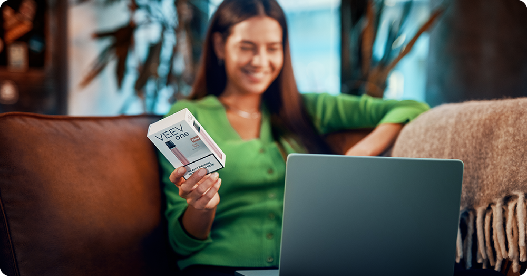 Femeie cu bluza verde, care ține în mână un dispozitiv VEEV