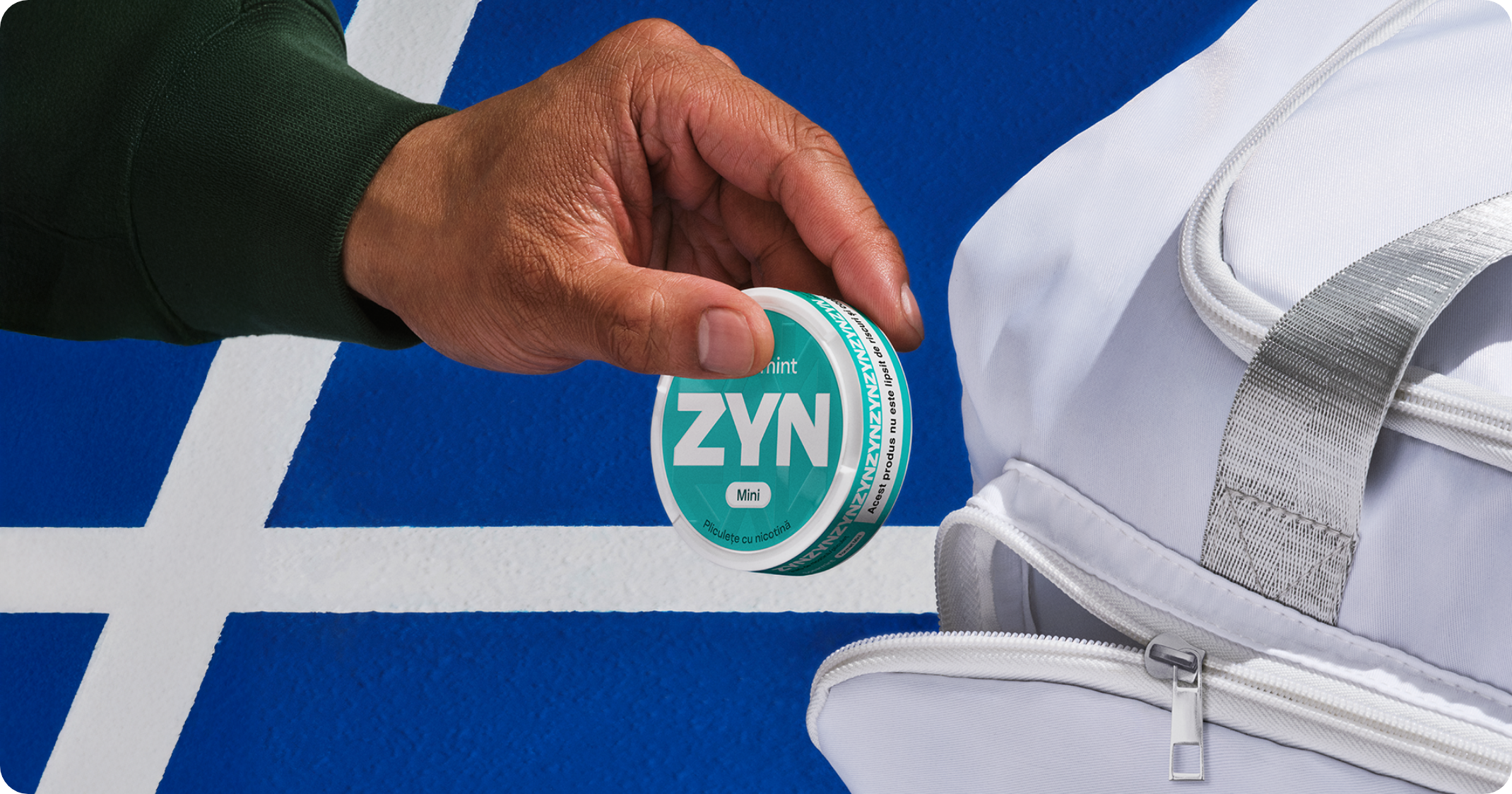 Bărbat cu bluza gri, care ține în mână un dispozitiv IQOS ILUMA