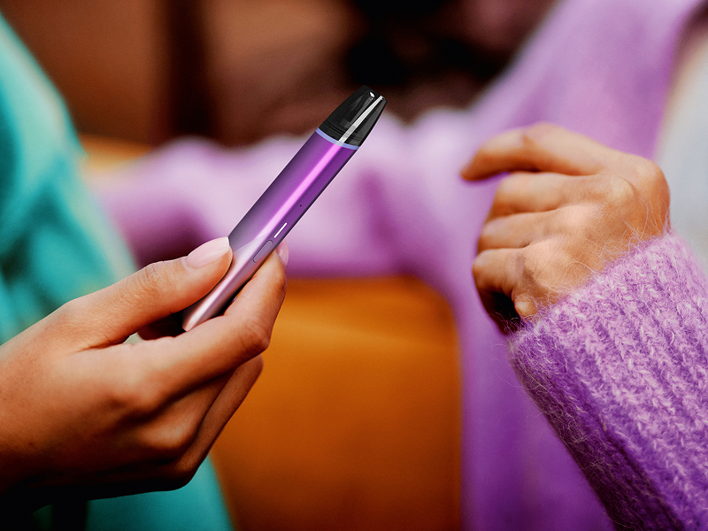 Imagine - Mână care înmânează un dispozitiv de vapat VEEV inPRIME magenta unei alte persoane