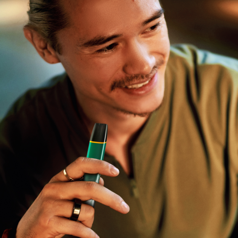 Imagine - Bărbat așezat ținând un dispozitiv de vapat VEEV verde - cum să vapezi corect