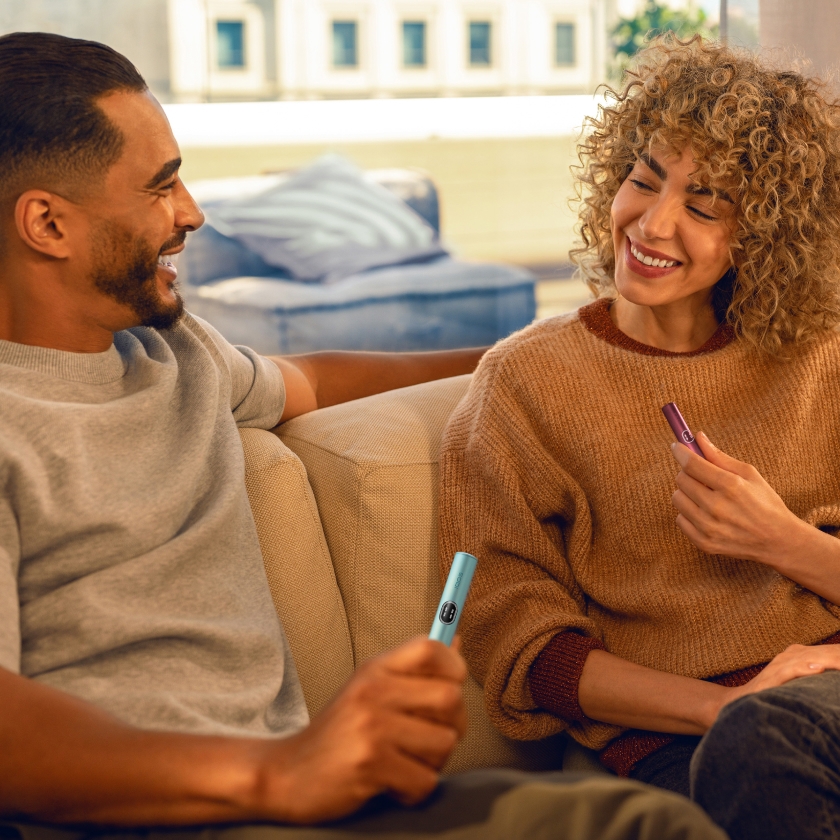 Un bărbat și o femeie care tin in mana cate un stilou IQOS ILUMA.