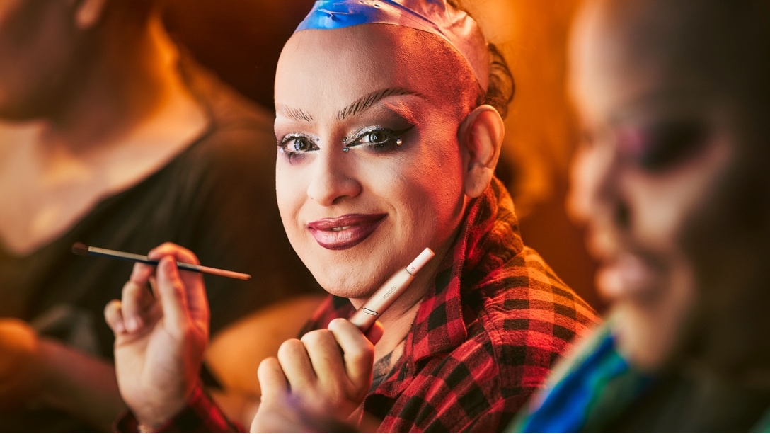 Un travestit ține în mână un dispozitiv IQOS..